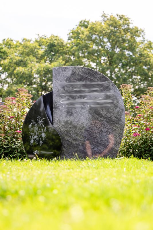 Modern rond grafmonument van grijs graniet met gezandstraalde bloemen