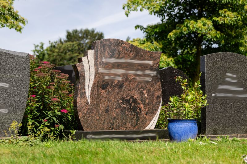 Waaiervormig grafmonument van roodbruin graniet met gezandstraald reliëf